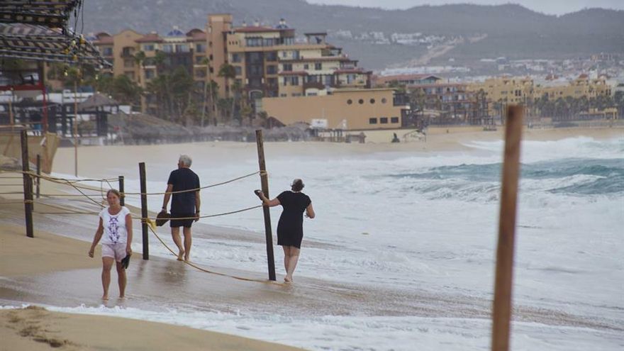 Un grupo de personas camina por una playa frente a fuertes olas en Cabo San Lucas el estado mexicano de Baja California Sur.