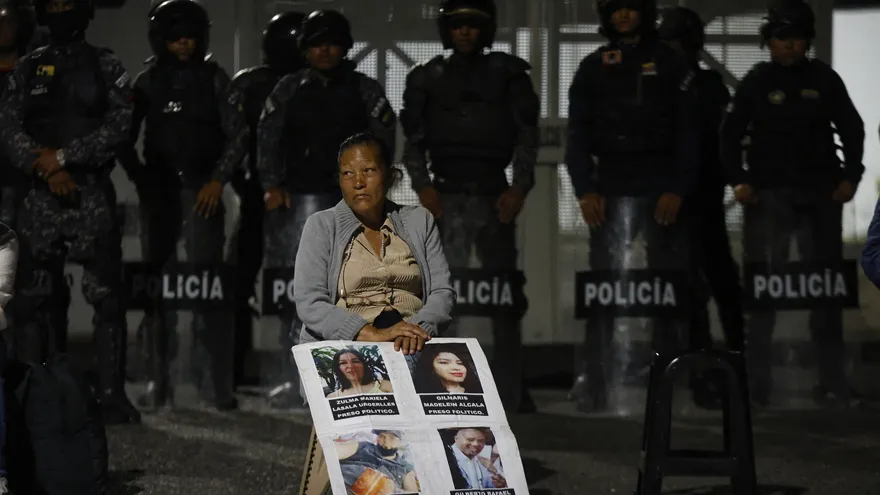 Una mujer con imágenes de prisioneros espera por noticias