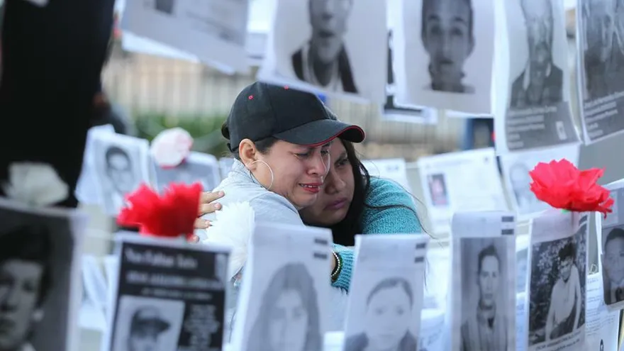 Dos mujeres observan fotografías de personas desaparecidas este viernes, en las afueras del Palacio Nacional, en Ciudad de México (México).