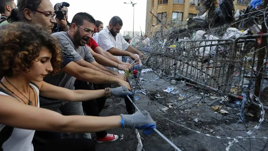 Activistas libaneses del movimiento "You Stink" tratan de quitar una barricada de alambre de púas durante una protesta frente al Palacio de Gobierno, Beirut, Líbano
