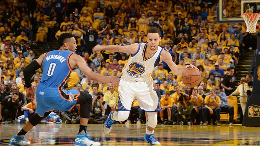 Stephen Curry (de frente) intenta evadir la cobertura de Russell Westbrook (de espalda)