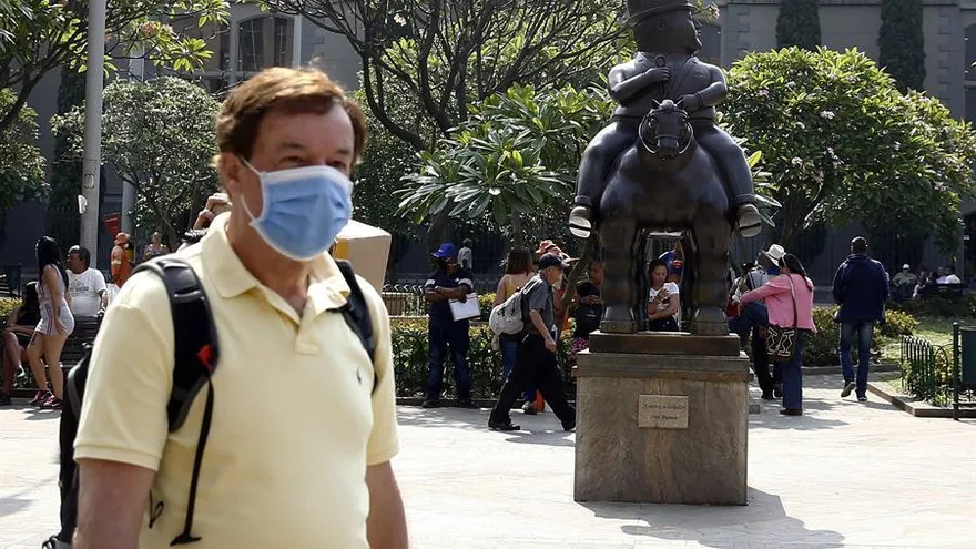 Un hombre con tapabocas camina cerca a una escultura de Fernando Botero como medida contra el coronavirus en Medellín.