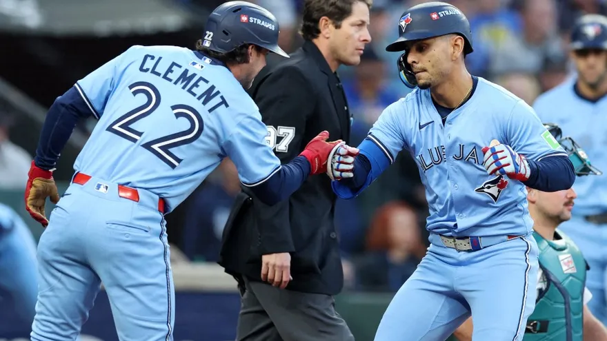 Andrés Giménez (d) celebra con Ernie Clement (i) tras conectar un cuadrangular ante los Marineros