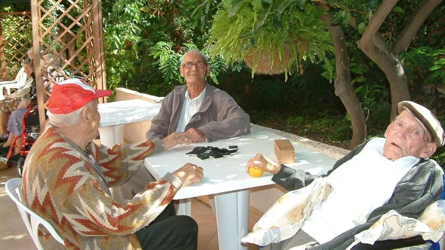 Un grupo de ancianos juega al dominó.