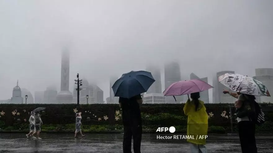 La gente se protege con una funda de lluvia desechable durante el paso del tifón Co-May en Shanghai el 30 de julio de 2025 Shanghai ha evacuado a casi 283.000 personas de las zonas costeras y bajas vulnerables a medida que se acerca el tifón Co-May, trayendo fuertes lluvias y vientos, informaron los medios estatales el 30 de julio.