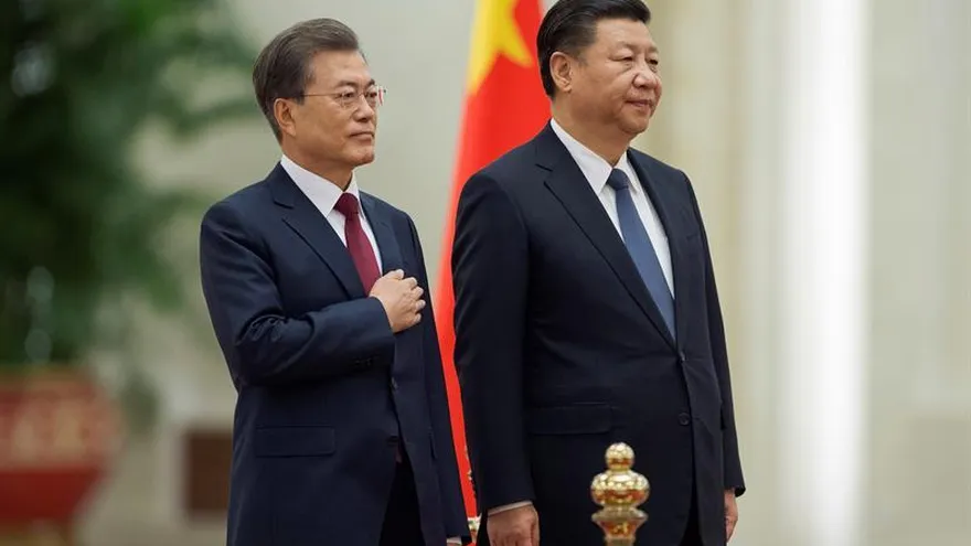 El presidente chino, Xi Jinping (d), y su homólogo coreano, Moon Jae-in (i), escuchan el himno surcoreano durante una ceremonia de bienvenida en el Gran Salón del Pueblo en Pekín (China), hoy 14 de diciembre de 2017.