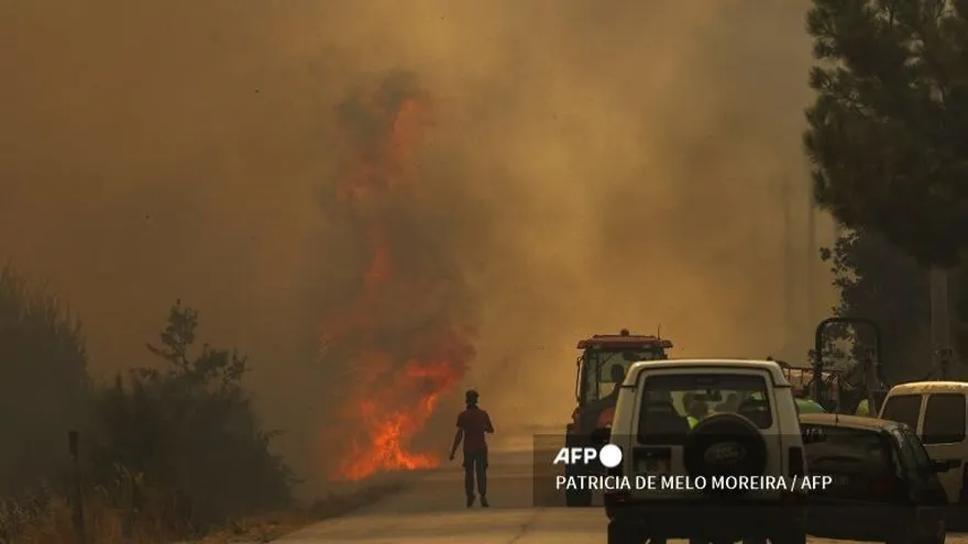 Un hombre corre hacia las llamas en una carretera cubierta de humo durante un incendio forestal en el pueblo portugués de Antas, en Trancoso, el 15 de agosto de 2025.