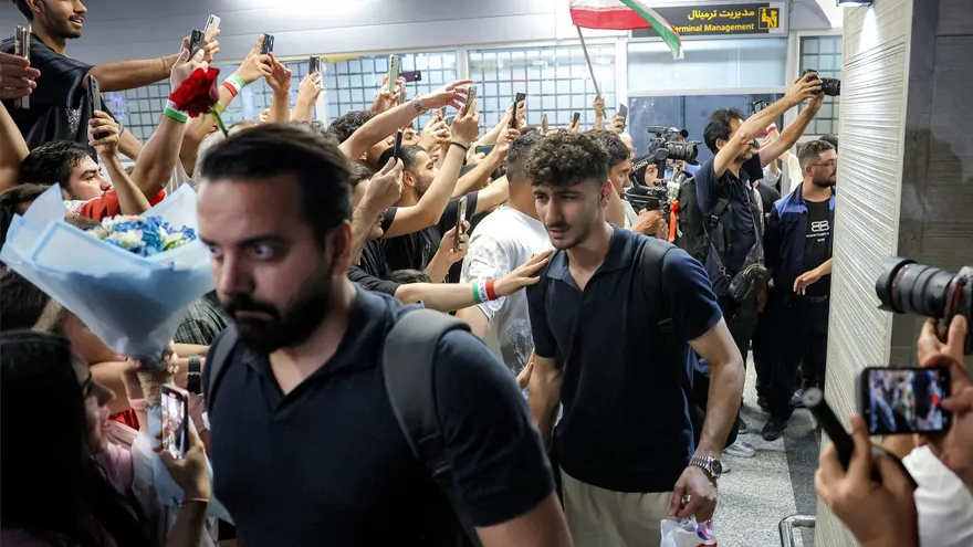 Jugadores de la selección de Irán pasan cerca de fanáticos que captan su llegada con celulares