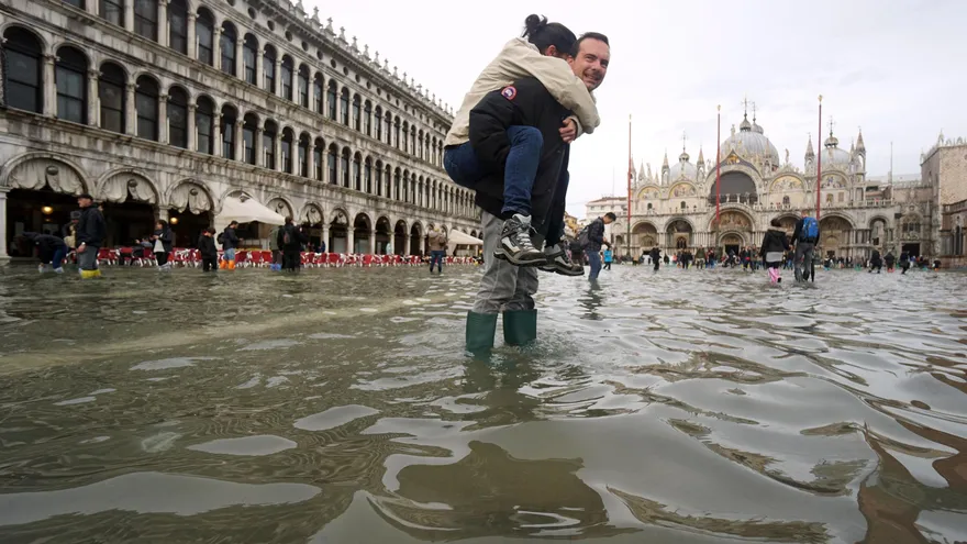Un hombre carga a sus espaldas con su hija en la Plaza de San Marco, inundada como consecuencia del temporal de lluvia registrado en Venecia