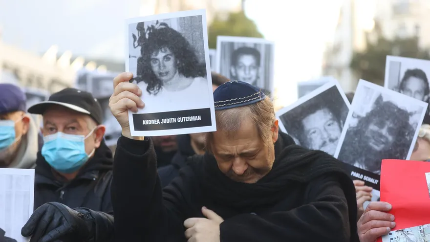 Un hombre muestra la imagen de una de las víctimas durante un acto conmemorativo por el 28 aniversario del atentado contra la Asociación Mutual Israelita Argentina