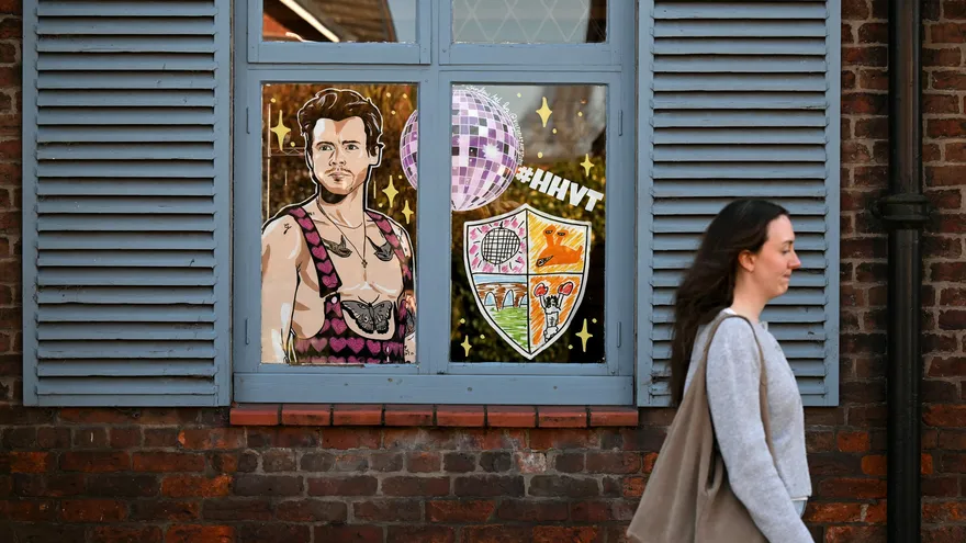 Una persona pasa cerca de la ventana de un negocio donde se observa la imagen de Harry Styles