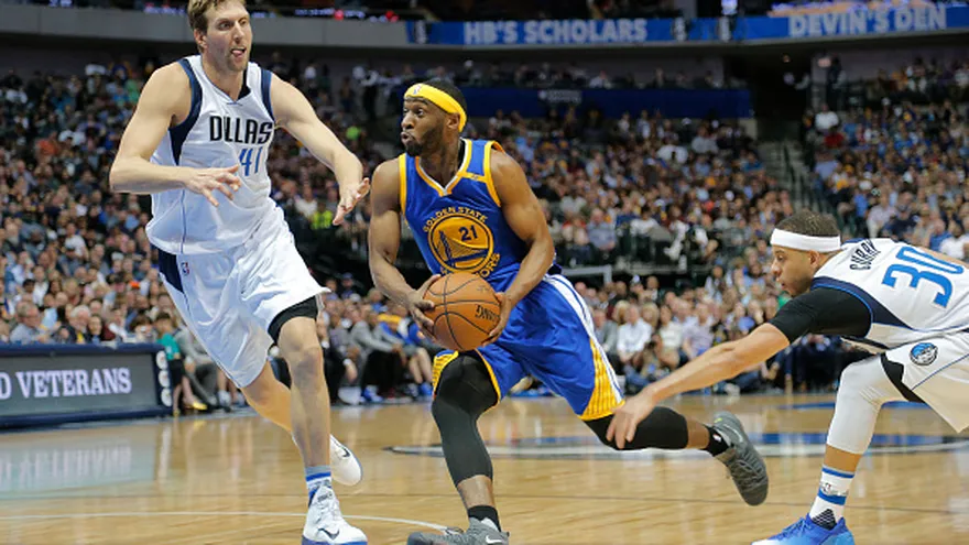 Ian Clark (21) se dirige a la canasta ante la cobertura de Dirk Nowitzki (41) y Seth Curry (30)