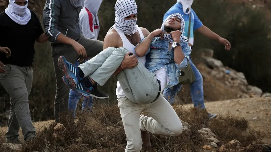Lanzadores de piedras palestinos cubiertos, durante los enfrentamientos con las fuerzas de seguridad israelíes en Beit El, cerca de la ciudad cisjordana de Ramallah el 10 de octubre de 2015.