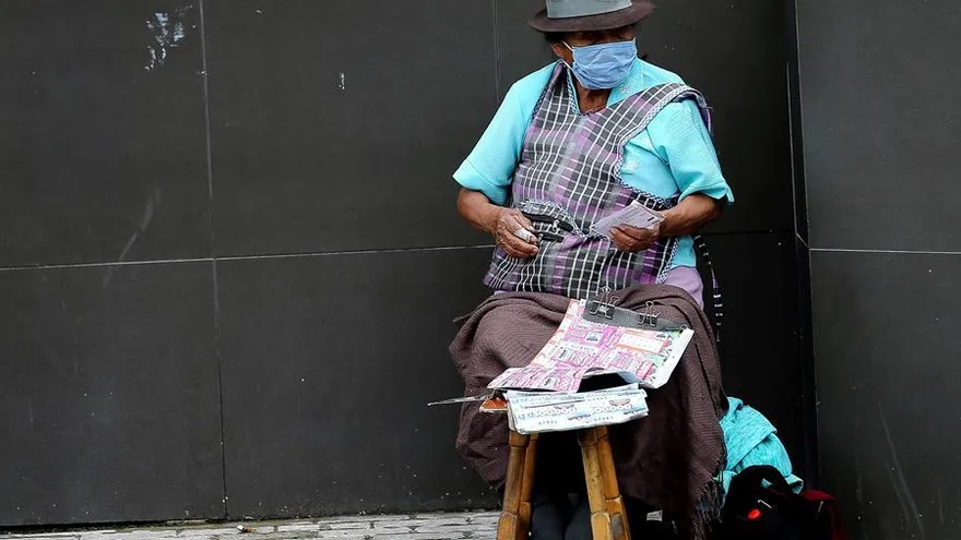 Una mujer con tapabocas vende lotería en las calles de Quito.