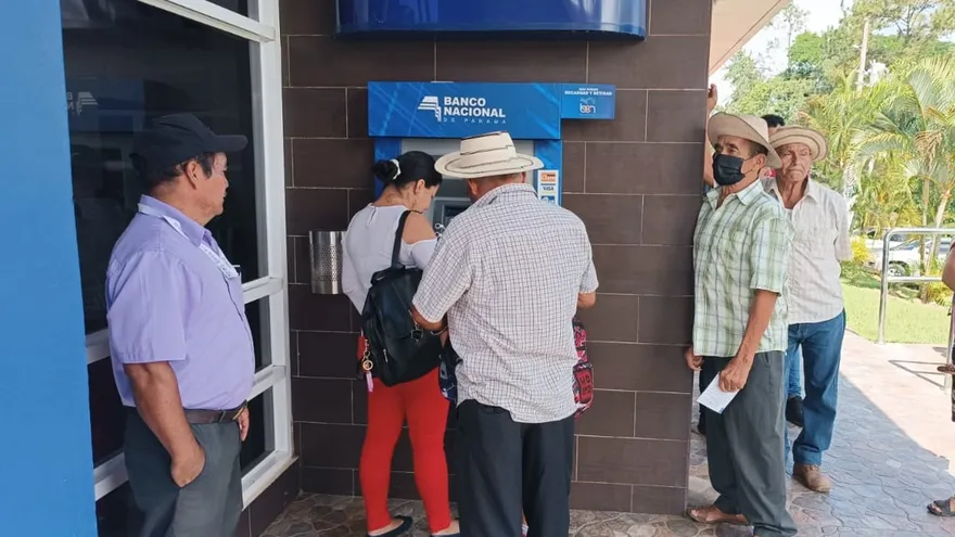 Un grupo de personas d ela tercera edad a la espera para utilizar un cajero automático