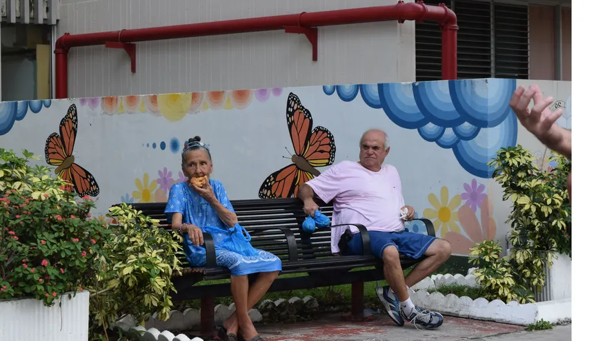 Dos ancianos comparten una silla en Miami, Florida