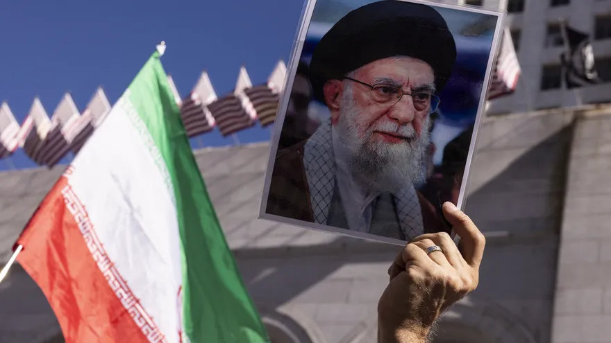 Una persona sostiene una imagen de Jamenei y una bandera de Irán