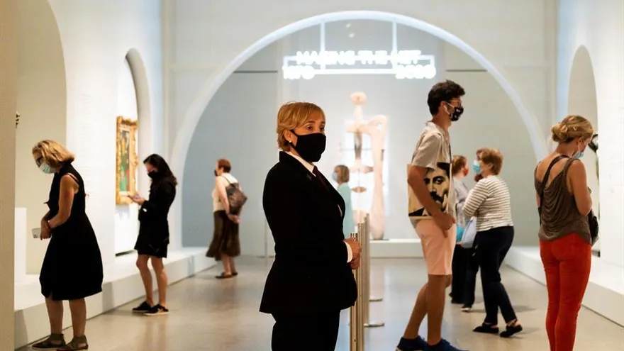 Fotografía tomada el pasado jueves 27 de agosto en la que se registró a una guarda de seguridad (c) y a un grupo de visitantes, durante la reapertura del Museo Metropolitano de Arte de Nueva York, que reabrió con la exhibición 'Making the Met, 1870-2020', en Nueva York (NY, EE.UU.).