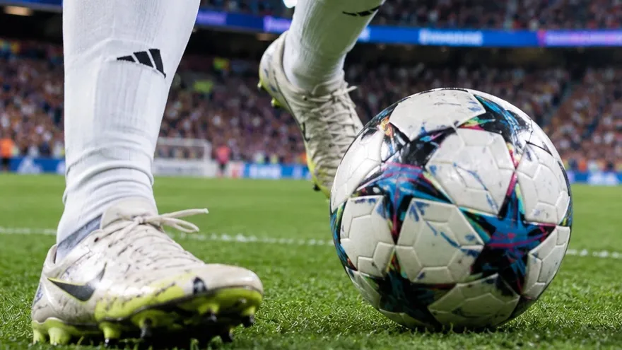Futbolista controlando el balón bajo las luces (imagen ilustrativa)