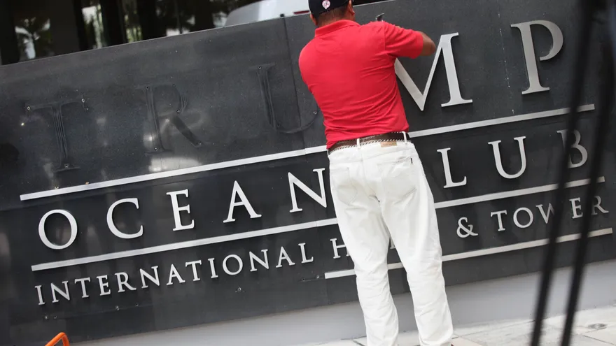 Un trabajador retira el letrero del Trump Ocean Club, mientras unidades de la policía nacional y representantes del Órgano Judicial de Panamá realizan un operativo en el edificio el 5 de marzo de 2018, en Ciudad de Panamá (Panamá).