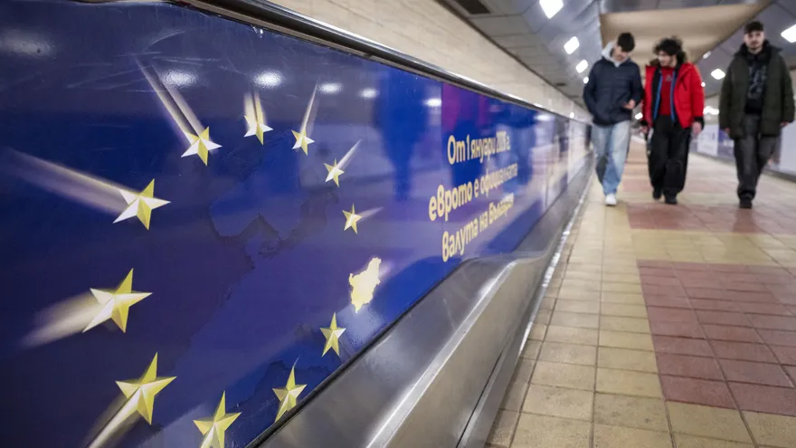 Personas pasan cerca de una publicidad del euro en Bulgaria