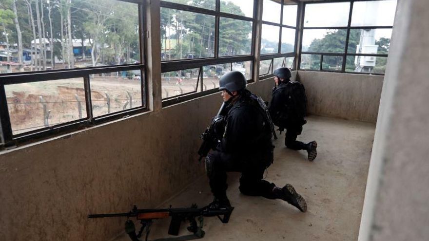 Agentes de la Policía de Guatemala aguardan frente a la cárcel de Pavón mientras se escuchan detonaciones de bala este martes, en el municipio de Fraijanes, a unos 25 kilómetros al sureste de la capital (Guatemala).