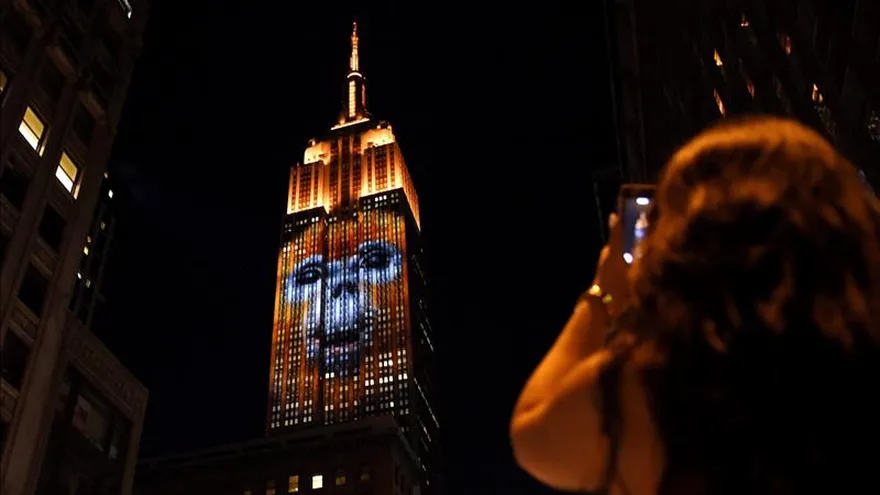 Una mujer fotografía el Empire State Building en cuya fachada se proyecta la imagen de una especie protegida en Nueva York.