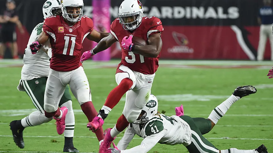 David Johnson (con el ovoide) intenta burlar a los defensores de los Jets