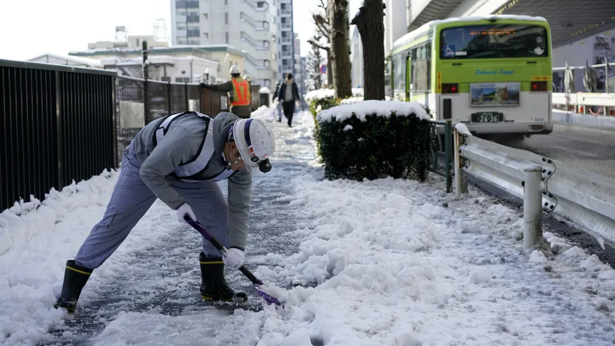Un trabajador despeja un andén después de una nevada en Tokio, Japón