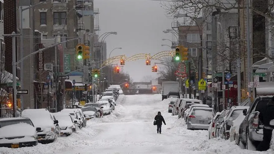 Una mujer camina por una calle cubierta de nieve en el barrio de Brooklyn en la ciudad de Nueva York, Estados Unidos.