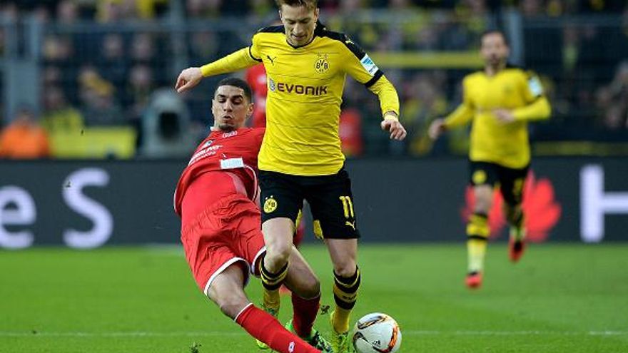 Marco Reus (de frente) recibe la barrida de Leon Balogun