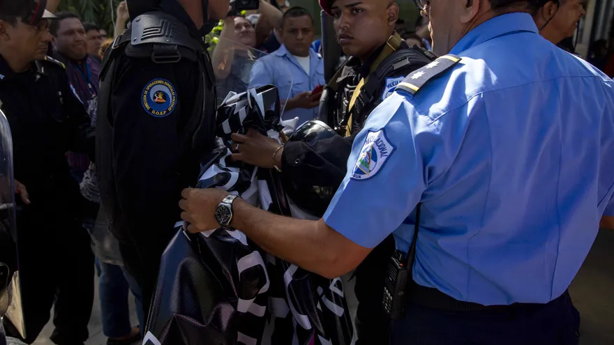 Miembros de la policía nacional arrebatan una pancarta a miembros del Centro Nicaragüense de Derechos Humanos (Cenidh) durante un plantón para pedir libertad de "presos políticos"