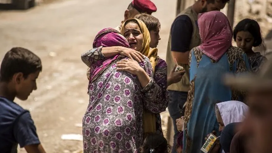 Una mujer iraquí, que huyó de los combates entre las fuerzas gubernamentales y los yihadistas del grupo Islámico (IS) en la Ciudad Vieja de Mosul, reacciona mientras abraza a otra dama.