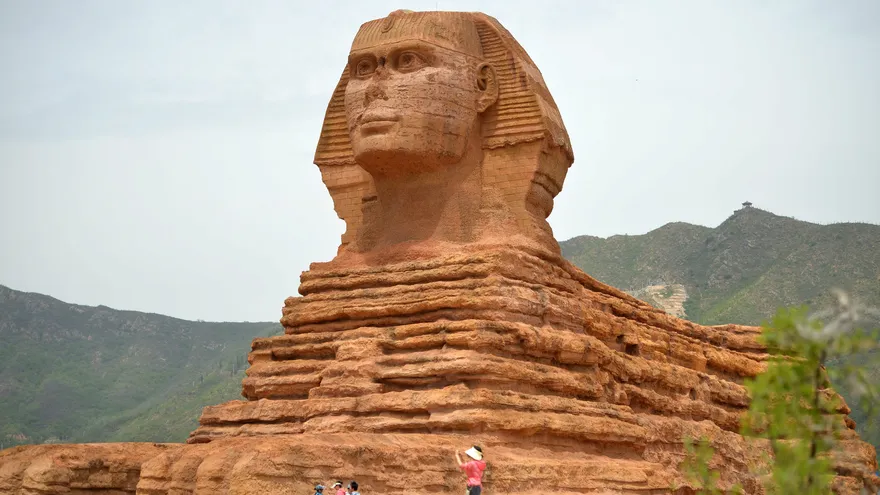 Visitantes conducen bicicletas frente a una replica en tamaño natural de la esfinge de Giza, de 20 metros de alta, en la localidad de Shijiazhuang, provincia de Hebei (China).