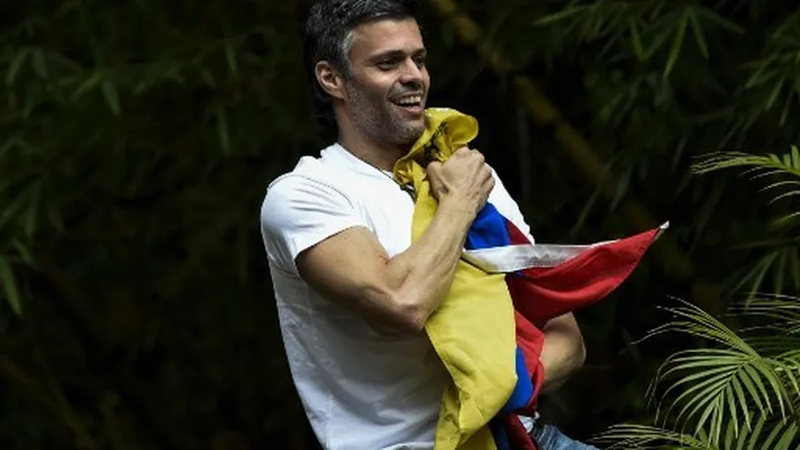 El líder de la oposición venezolana, Leopoldo López, exhibe la bandera nacional venezolana mientras saluda a los partidarios que se reúnen fuera de su casa en Caracas.