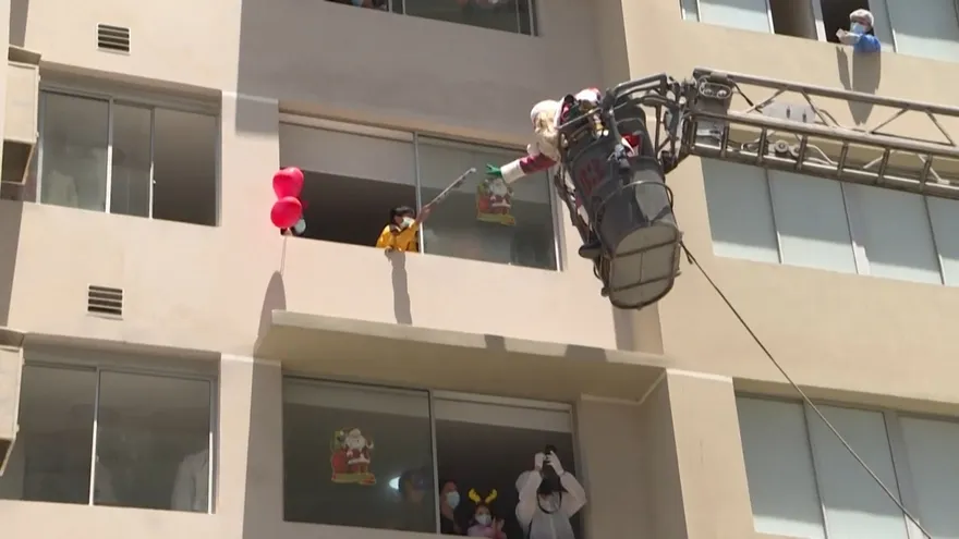 En escalera de bomberos Papá Noel entrega regalos a niños con covid-19 en Perú