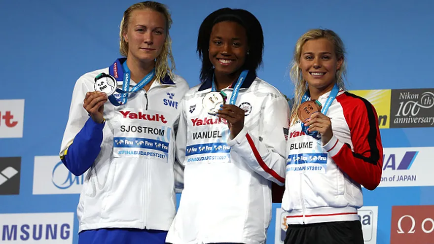 Simone Manuel (c) en el podio junto a  sorprende a Sarah Sjöstrom (i) y Pernille Blume (d)