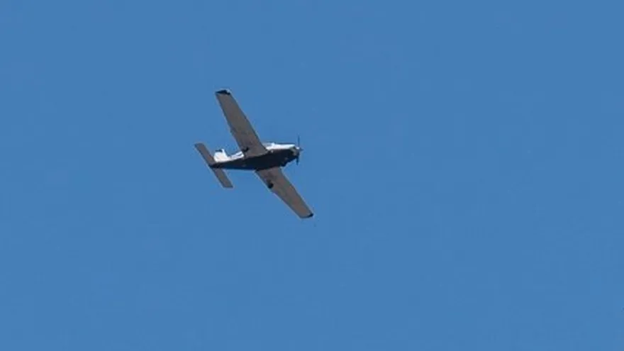 Una avioneta sobrevuela el lugar donde otra avioneta se estrelló contra un vecindario, incendiando viviendas y vehículos el 22 de mayo de 2025 en San Diego, California.