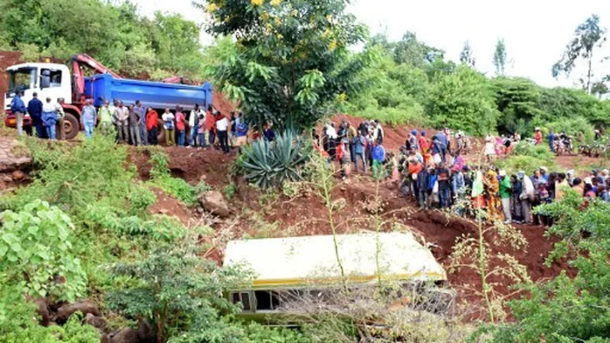 La gente observa los restos de un autobús que transportaba a alumnos de primaria de Arusha a Karatu antes de sumergirse en un barranco.