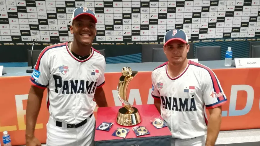 Benjamín Bailey (i) y Dimas Ponce (d) posan junto al trofeo del Mundial de Béisbol Sub-18