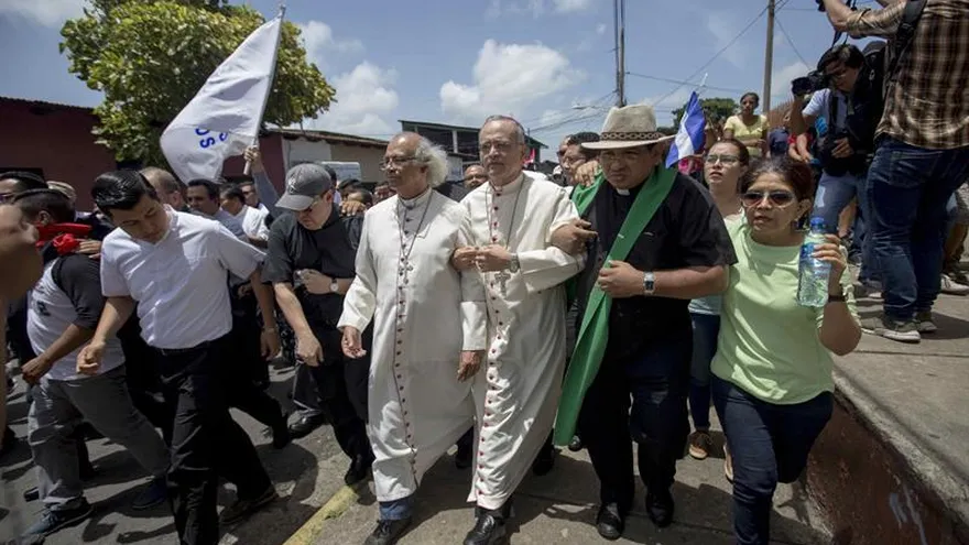 El cardenal Leopoldo Brenes (c-i) y el obispo Silvio Báez (d) caminan frente a la basílica de San Sebastián para liberar a un grupo de paramédicos y misioneros franciscanos sitiados por parapolicías en el templo ayer, lunes 9 de julio de 2018, en la ciudad de Diriamba (Nicaragua).