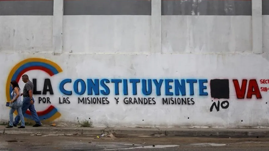 Un pareja camina frente a una pared con propaganda de la Asamblea Nacional Constituyente hoy, sábado 15 de julio de 2017, en Caracas (Venezuela).
