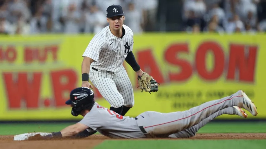 Anthony Volpe (de pie) cerca de Nick Sogard quien se desliza sobre la segunda base