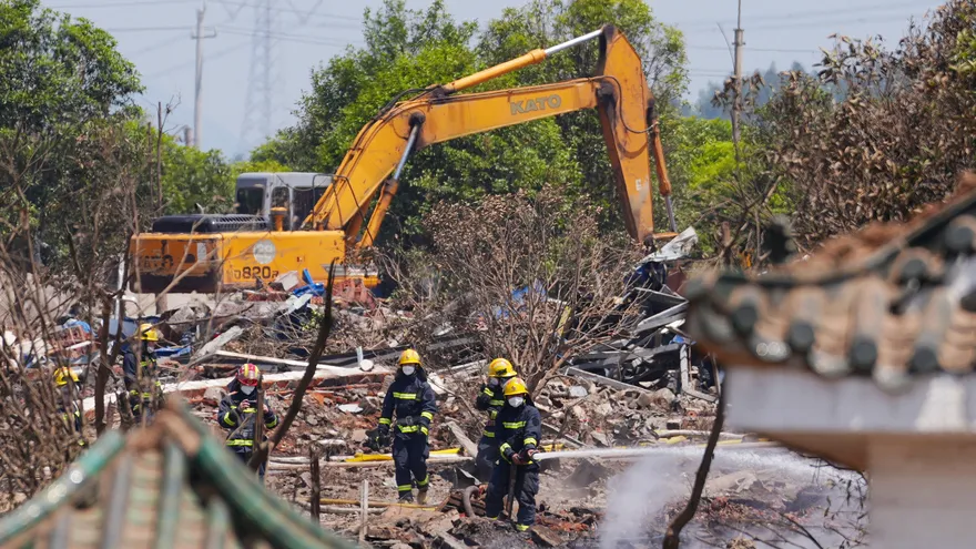 Los bomberos rocían agua en el lugar de la explosión de una fábrica de fuegos artificiales en Liuyang