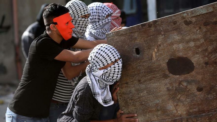 Varios manifestantes palestinos se protegen de los disparos de las tropas israelíes en el campo de refugiados de Aroub, en la ciudad de Hebrón, al norte de Cisjordania.