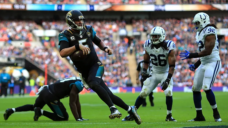 Blake Bortles acarrea el balón ante dos jugadores de los Colts