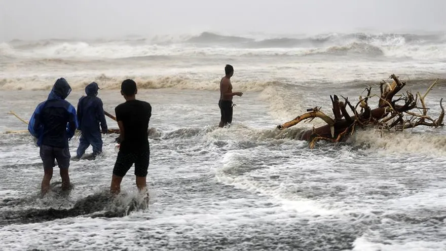 Varios filipinos juegan con las olas en la ciudad de Aparri, Filipinas, el 15 de septiembre de 2018, ocasionadas por el paso de Mangkhut, el tifón más poderoso en los últimos cinco años.