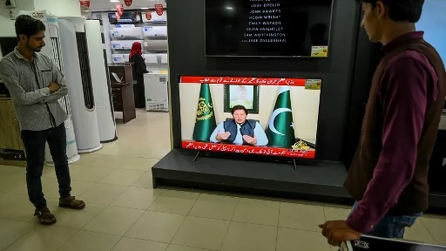 Personas observan al primer ministro paquistaní Imran Khan hablar por televisión