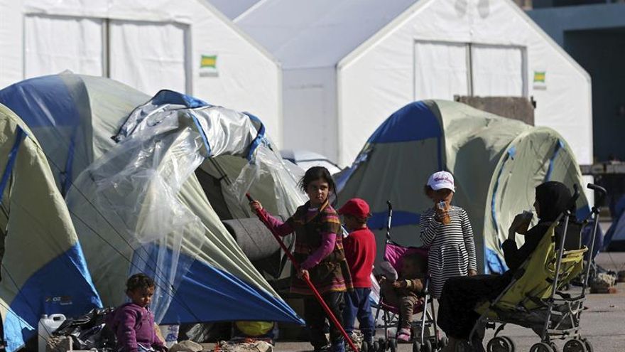 Una familia frente a su tienda de campaña, en el campamento de refugiados levantado en el puerto del Pireo (Grecia).