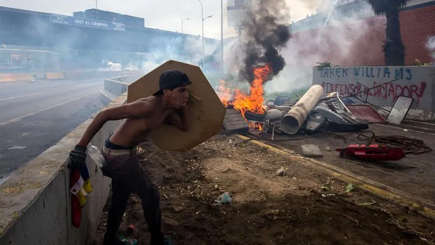 Un manifestante se protege durante una confrontación con miembros de la Guardia Bolivariana este 3 de mayo de 2017, en Caracas (Venezuela).